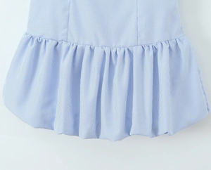 Close-up of blue and white striped fabric with ruffled hem and textured cotton finish