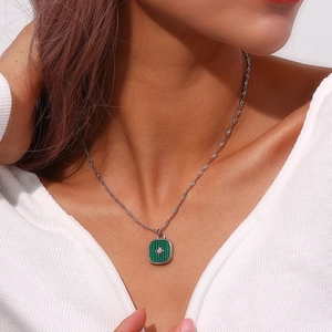 Detail view of model wearing a green rectangular star pendant necklace with twisted rope chain