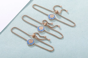 Dettaglio di braccialetti zodiaco in oro rosa con smalto blu e chiusura a scorrimento