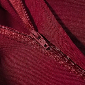 Macro detail of high-quality metal zipper and twill fabric texture on burgundy blazer