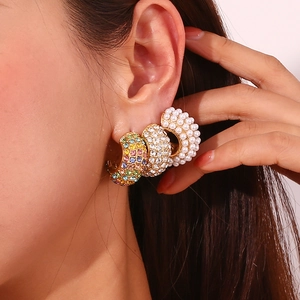 Macro detail of 18K gold plated C-shaped earrings with rhinestones and white pearls