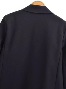 Detail of a black blazer featuring a notched lapel and smooth woven fabric on the back