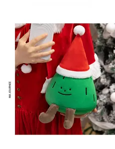 Close-up of a plush Christmas tree doll with a red Santa hat held in hands for holiday gifting