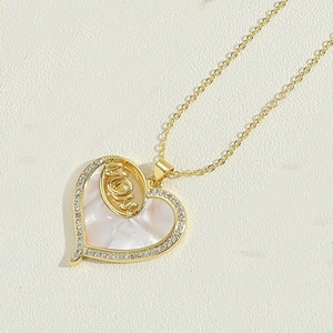 Detailed macro shot of golden heart pendant with white mother of pearl and MOM design