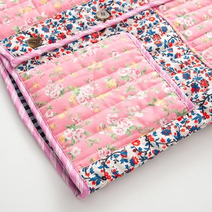 Gros plan sur une veste matelassée en coton à motifs floraux avec poches et boutons sombres