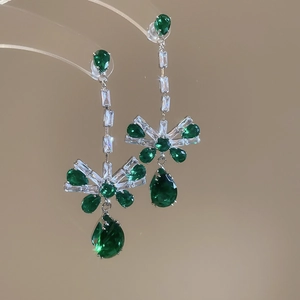 Detail of silver bow earrings with pear-cut green zircon and clear faceted stones