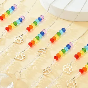 Rainbow crystal suncatcher with silver paw charms hanging as colorful outdoor window decor