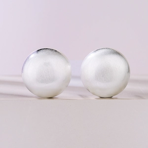 Close-up of matte silver geometric round stud earrings with brushed metallic texture