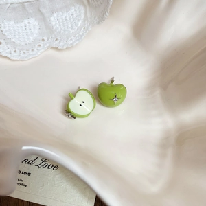 Detail view of cute green apple stud earrings with zirconia on a white ceramic tray