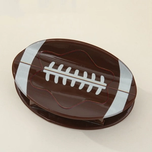 Close-up of brown rugby-shaped hair claw clip with glossy finish and white stitch details