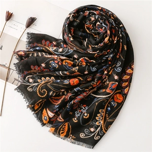 Detail of bohemian paisley print scarf with fringe edges on minimalist white surface