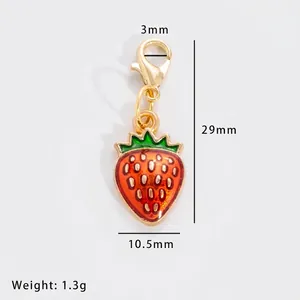 Detailed view of red strawberry pendant charm with lobster clasp and gold accents
