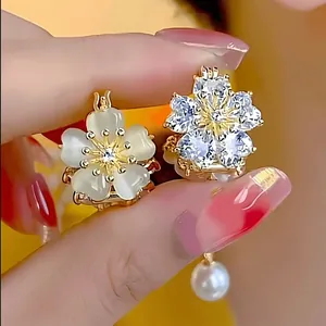 Close-up of double-sided floral earrings featuring white cat eye stone and sparkling zircons