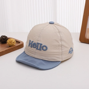 Détail d'un chapeau soleil pour bébé beige avec broderie Hello bleue et motif smiley