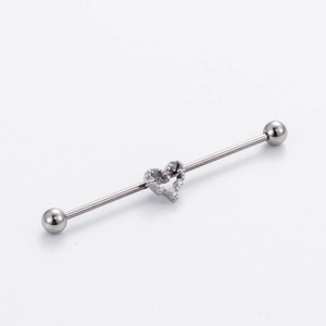 Detailed macro of silver industrial barbell earring featuring a heart with cubic zirconia