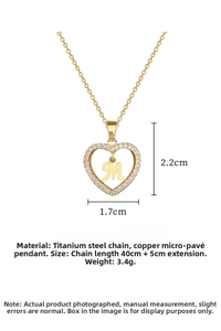 Detail view of heart necklace with M initial and white cubic zirconia on gold chain