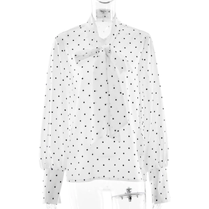 Détail du chemisier blanc à pois élégant avec col à nouer et manches longues fluides