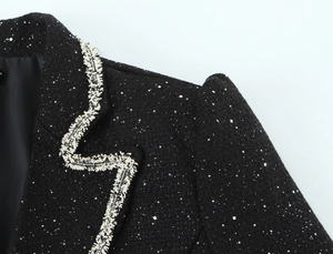 Detailed view of black tweed jacket with silver sequins and white fringe trim texture