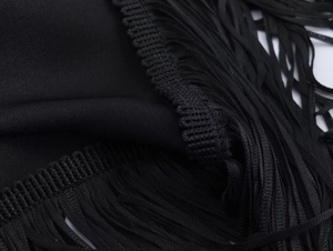 Close-up of silky black satin fabric with intricate fringe detail and expert stitching