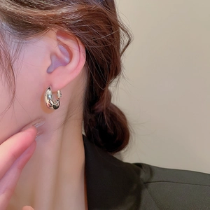 Gros plan de boucles d'oreilles créoles argentées en forme de U portées par un mannequin