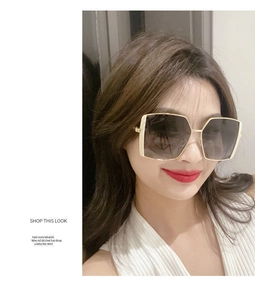 Detailed close-up of oversized square sunglasses with gold metal frame and gradient lenses