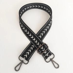 Close-up of adjustable nylon bag strap with black geometric embroidery and metal hooks