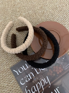 Close-up of three plush headbands in beige, dark brown and black on a magazine