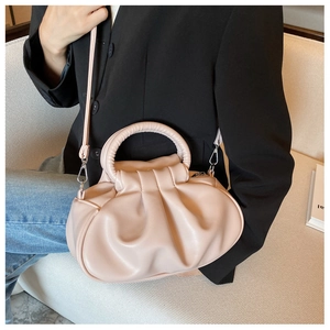 Detail of light pink ruched cloud bag featuring a metal ring handle and soft texture