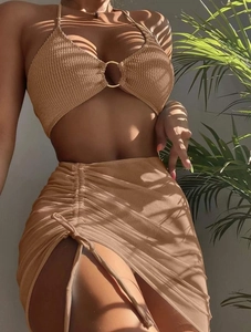 Detail of tan three-piece bikini with gold ring connector and drawstring skirt