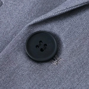 Gros plan sur le tissu gris tissé et les détails d'un bouton noir mat à quatre trous