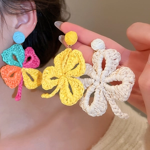 Close-up of handmade raffia flower earrings in vibrant colors for vacation style