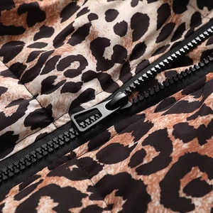 Détail d'une fermeture éclair noire sur un manteau matelassé à imprimé léopard chic