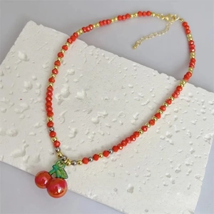 Detail of red beaded cherry pendant necklace with gold chain and imitation pearls