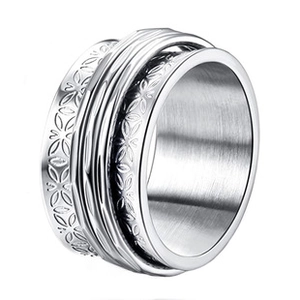 Detail of a rotating stainless steel ring with laser-cut floral patterns and brushed finish
