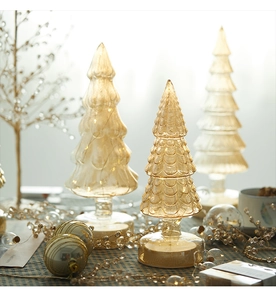 Close-up of lighted glass Christmas trees with warm LED lights and textured glass finish