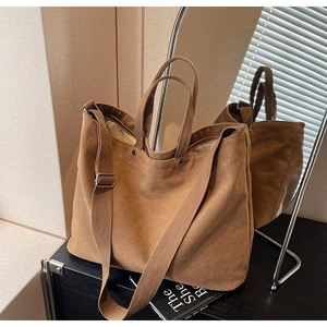 Detail of a brown canvas tote bag with adjustable strap on a minimalist black surface