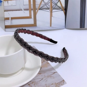 Detailed close-up of a black braided headband with delicate beaded pearl embellishments