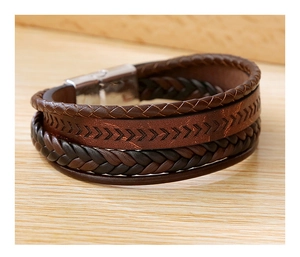 Detailed view of layered brown leather woven bracelets with rustic metal clasp on wood