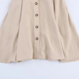 Detailed view of dark amber buttons on a khaki sleeveless midi dress with plain weave fabric