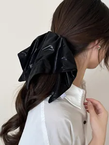Close-up of black metallic luster hair scrunchie with long ribbons on a ponytail