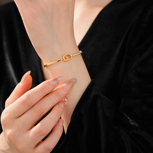 Close-up of 18k gold plated bracelet with zirconia buckle on a black fabric backdrop