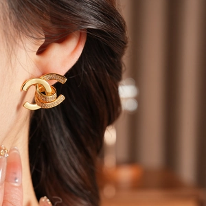 Close-up of 18k gold plated double C stud earrings with zircons on model's ear