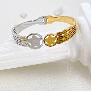 Detail of two-tone gold and silver star bangle with wavy texture on white pillar
