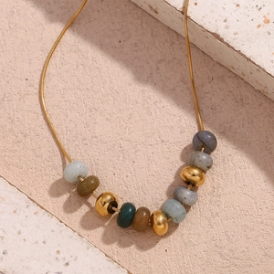 Détail de perles en pierre naturelle et perles dorées polies sur une chaîne serpent
