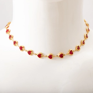 Detailed view of red heart gemstones on a gold-plated chain displayed on a white bust