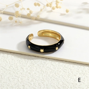 Detail of 18K gold plated open ring featuring black enamel and gold star patterns