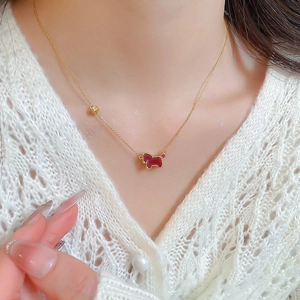 Detail of gold necklace with red pony pendant and small gold bead on a model's neck