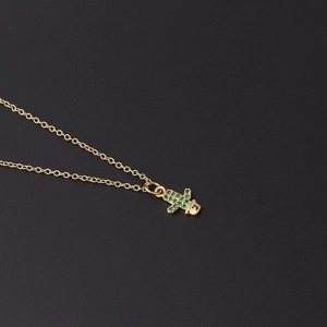 Detailed macro view of a gold cactus pendant necklace inlaid with sparkling green zircon