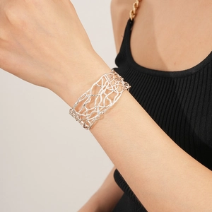 Gros plan du bracelet jonc ajouré argenté au poignet avec un design élégant et minimaliste