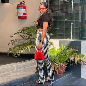 Vue latérale du pantalon évasé à rayures, taille haute, avec crop top et sac à main rouge